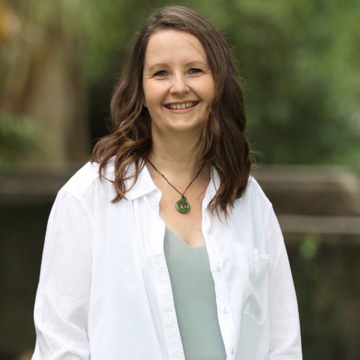 Rachel Mackay, standing outdoors in a white shirt, smiling at the camera